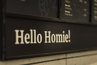 White text on a black background reads 'Hello Homie!' and is part of a menu board in a casual cafe setting.