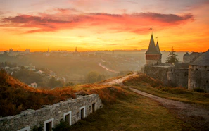 A Minecraft landscape featuring a handcrafted castle under a sunset sky.