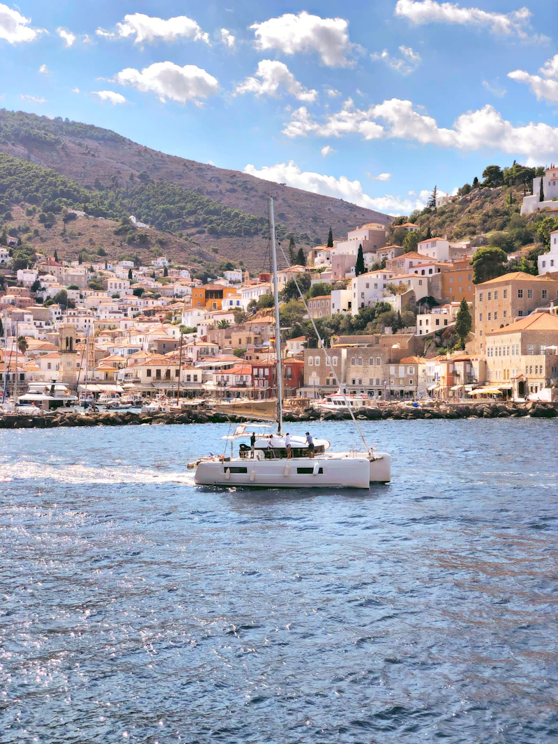 A boat leaving Hydra harbour, with stone mansions on the slopes