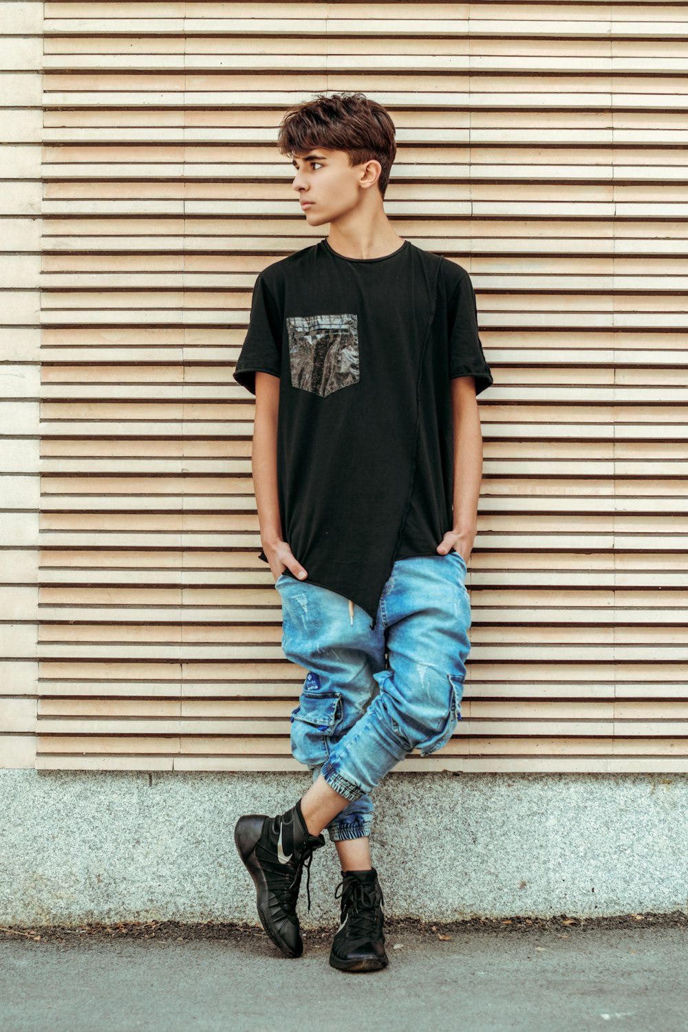 man in black crew neck t-shirt and blue denim jeans sitting on gray concrete floor