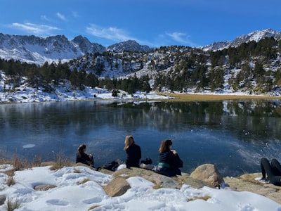 people sitting on rock near lake during daytime andorra teams background