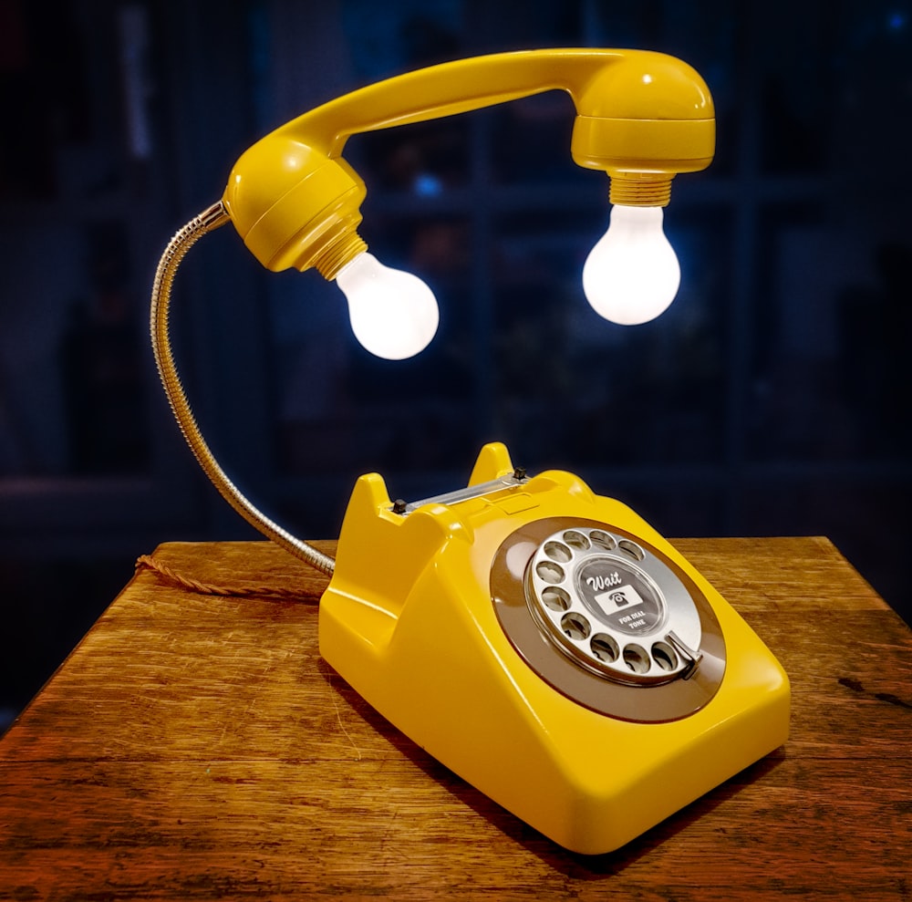 Téléphone à cadran rouge et blanc sur table en bois brun