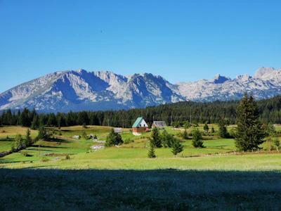 A meadow and a farmhouse below the limestone peaks of Durmitor