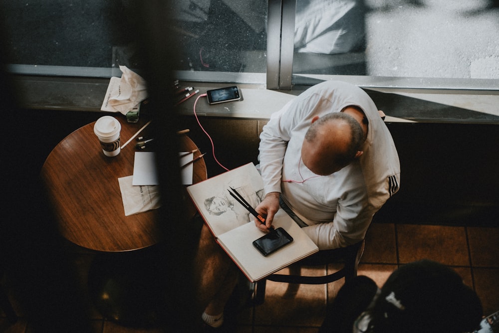 man in white dress shirt writing on white paper