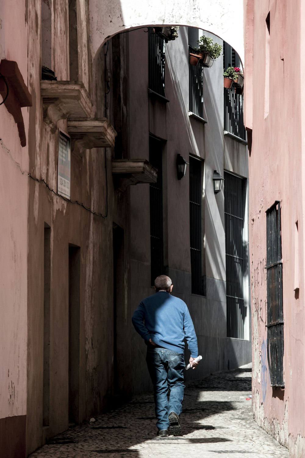 昼間、茶色のコンクリートの建物の前に立つ青いジャケットを着た男性