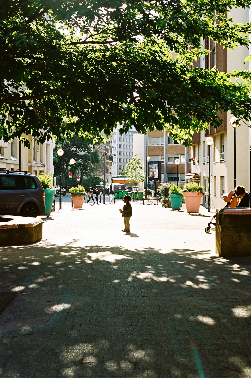 people walking on sidewalk near green car during daytime