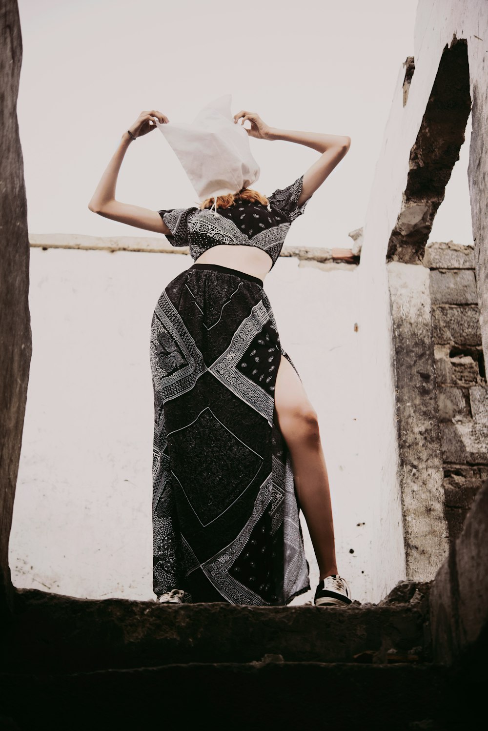 woman in white and black dress leaning on wall