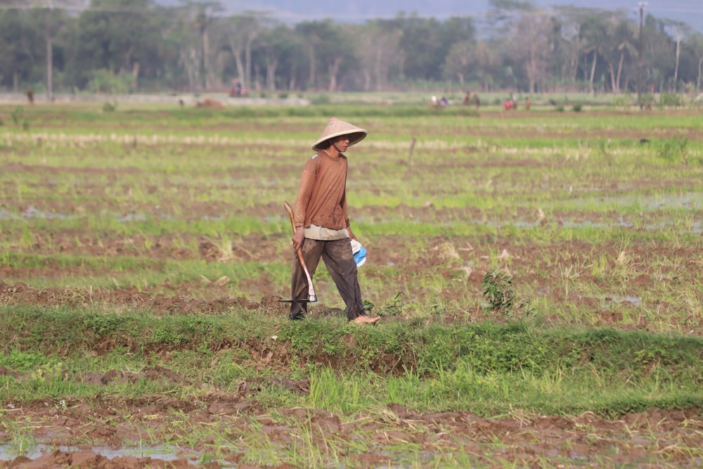 man in brown jacket and black pants walking on green grass field during daytime