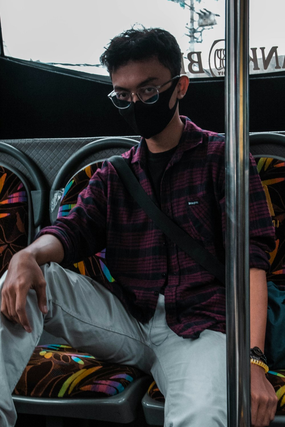 hombre con camisa de vestir a cuadros rojos y negros con gafas de sol negras conduciendo un coche