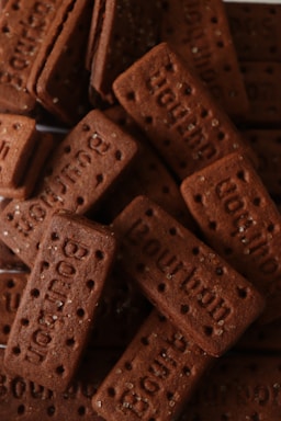 A collection of rectangular chocolate biscuits, each with the word 'Bourbon' embossed on top and small sugar granules sprinkled across the surface.