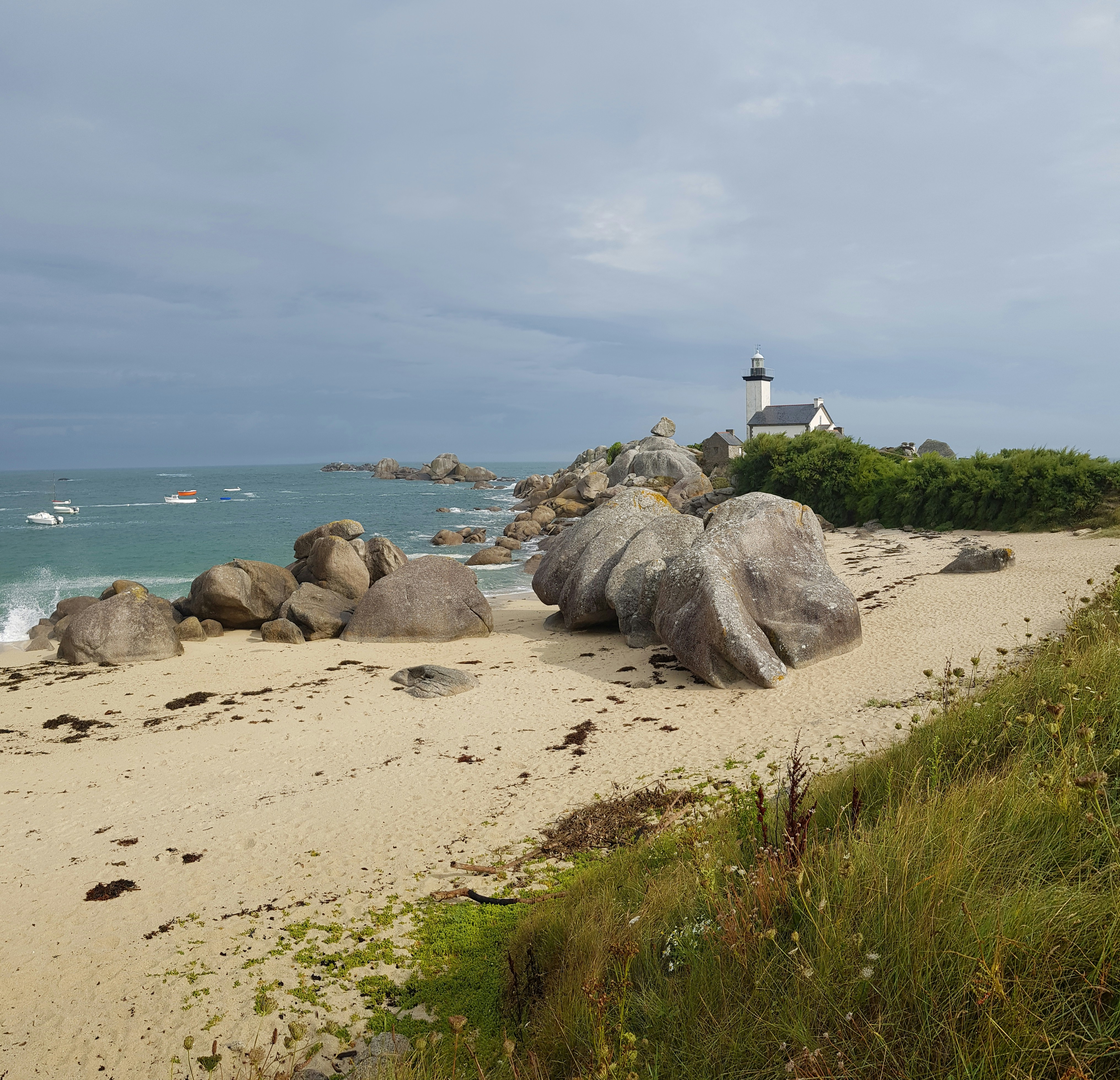 white lighthouse on gray rock formation near body of water during daytime