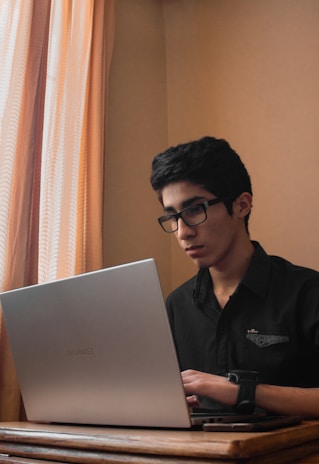 man in black polo shirt using gray asus laptop