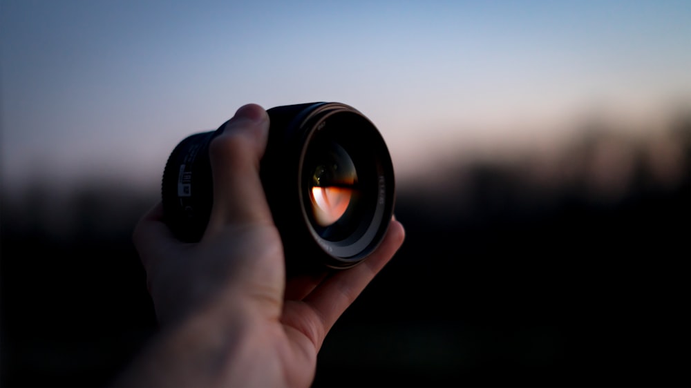 person holding black camera lens