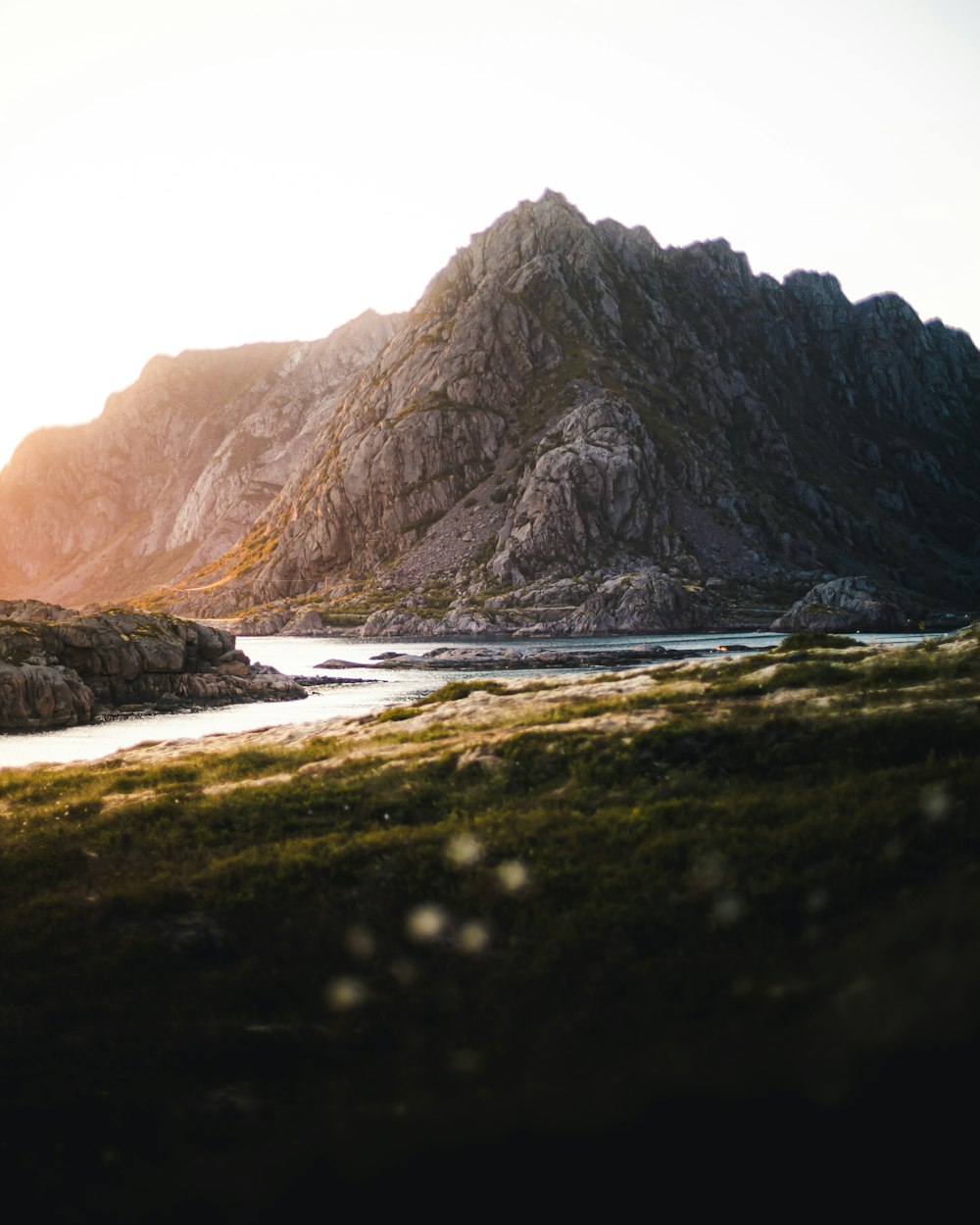 black rocky mountain beside body of water during daytime