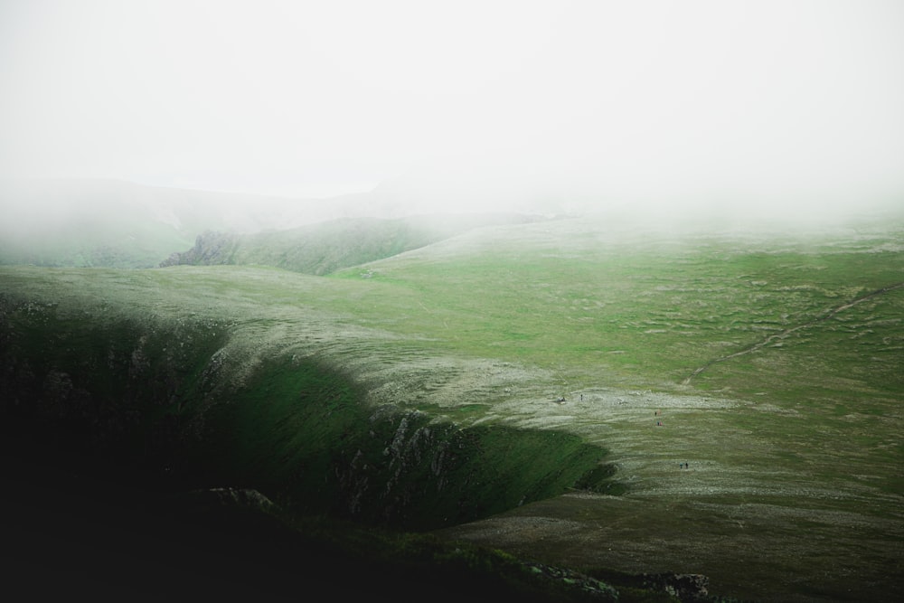 green grass covered hill under white sky during daytime