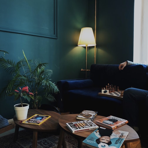 A cozy living room corner featuring a velvet emerald green armchair beside a sleek gold floor lamp.