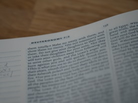 A close-up of an open book focusing on a passage from Deuteronomy 7:3-4. The text appears typed in a standard font and is slightly out of focus.