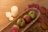 Wooden tray used as a centerpiece on a rustic dining table with candles and seasonal decor.