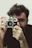 Portrait of Alexandre Calandrini smiling, holding his vintage camera.