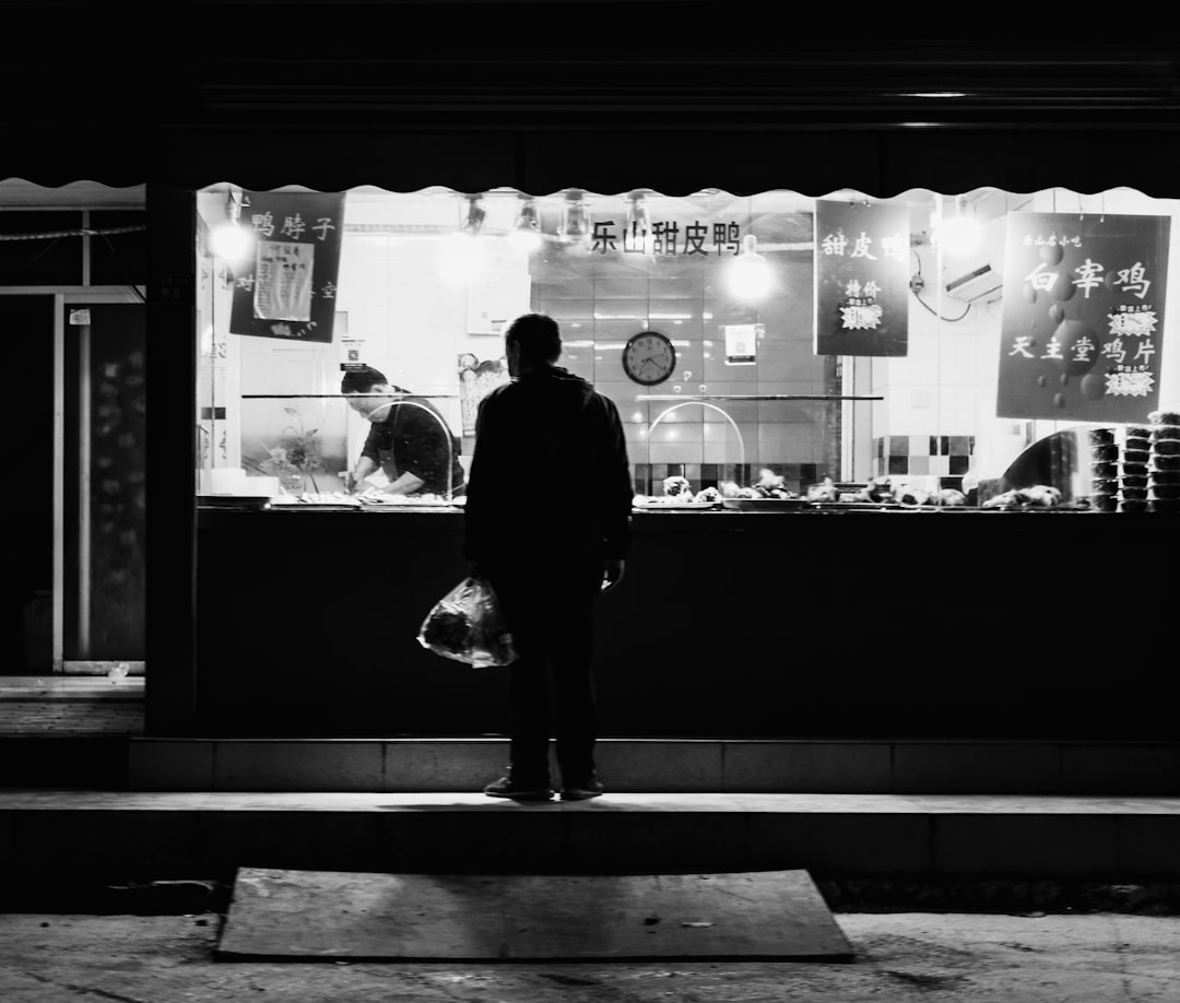 man in black coat standing in front of store