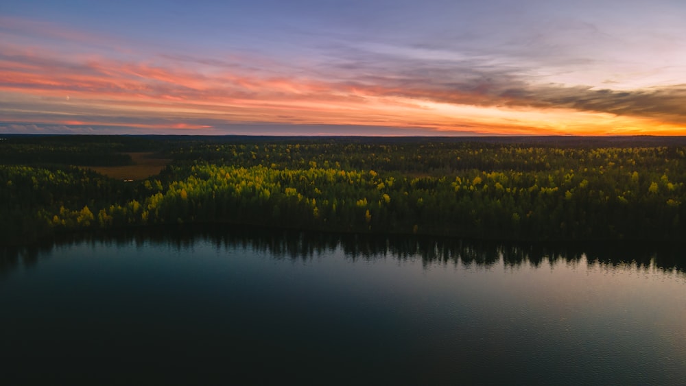 green grass field near lake during sunset