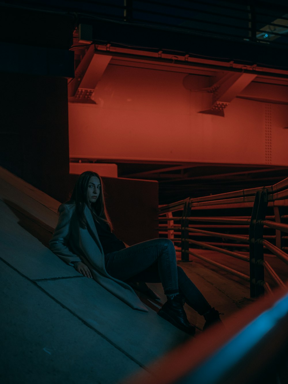 Frau in schwarzer Jacke und blauer Jeans sitzt auf der Treppe