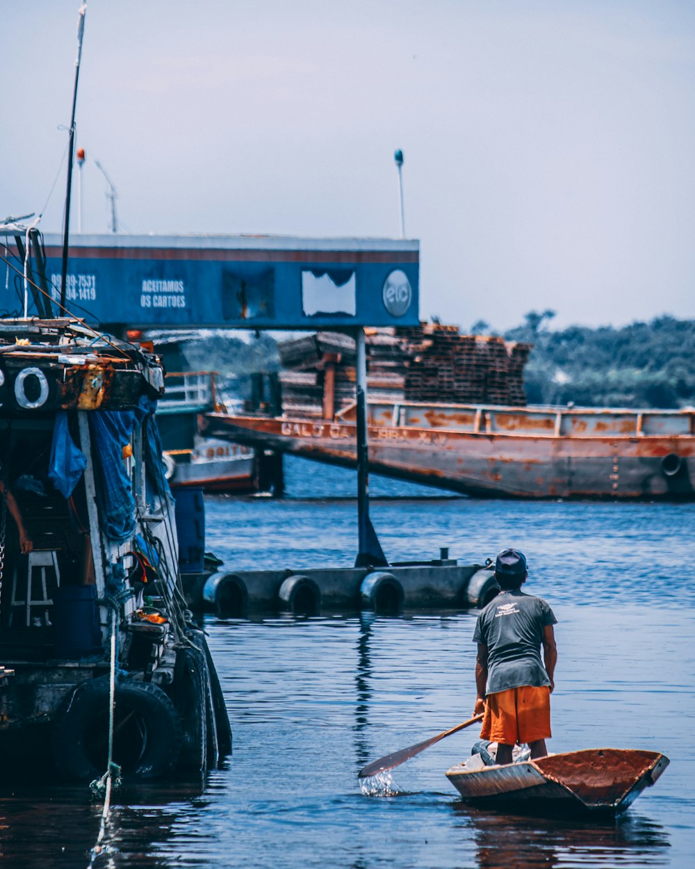 hombre con camisa gris y pantalones cortos naranjas pescando en el río durante el día