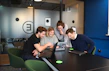 Office workspace with tech consultants discussing projects around a laptop