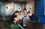 A diverse group of people smiling and discussing documents in a bright office setting.