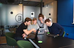 A dynamic team meeting in a modern office, collaborating over digital devices.