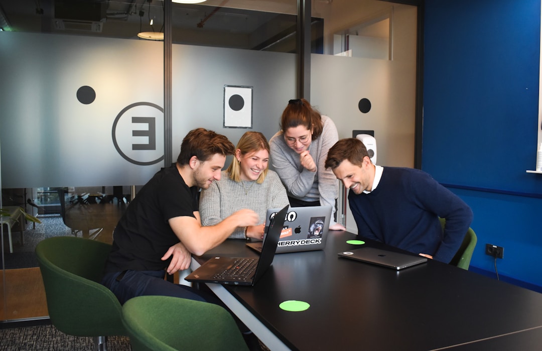 Four people smiling and looking at a laptop after implementing cloud faxing solutions.