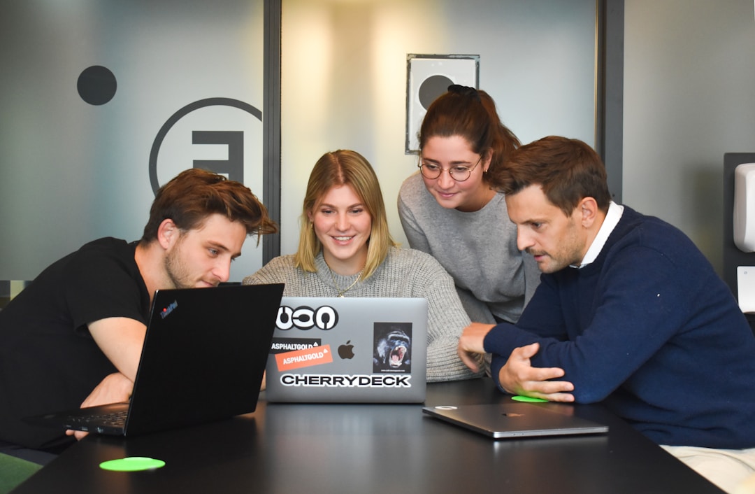 Four people looking at a laptop learning about what is proposal automation.