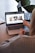 A person wearing a gray sweater is pointing to a laptop screen displaying a web page. The webpage contains a header titled 'Inspiration and Opportunities You Can't Miss' and features three sections with images and text. Nearby, there is another laptop on the table.
