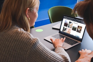 woman in gray sweater using macbook pro