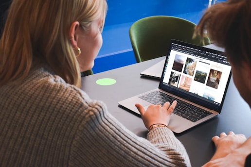 woman in gray sweater using macbook pro
