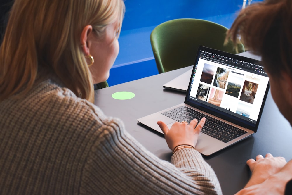 Frau in grauem Pullover mit MacBook Pro