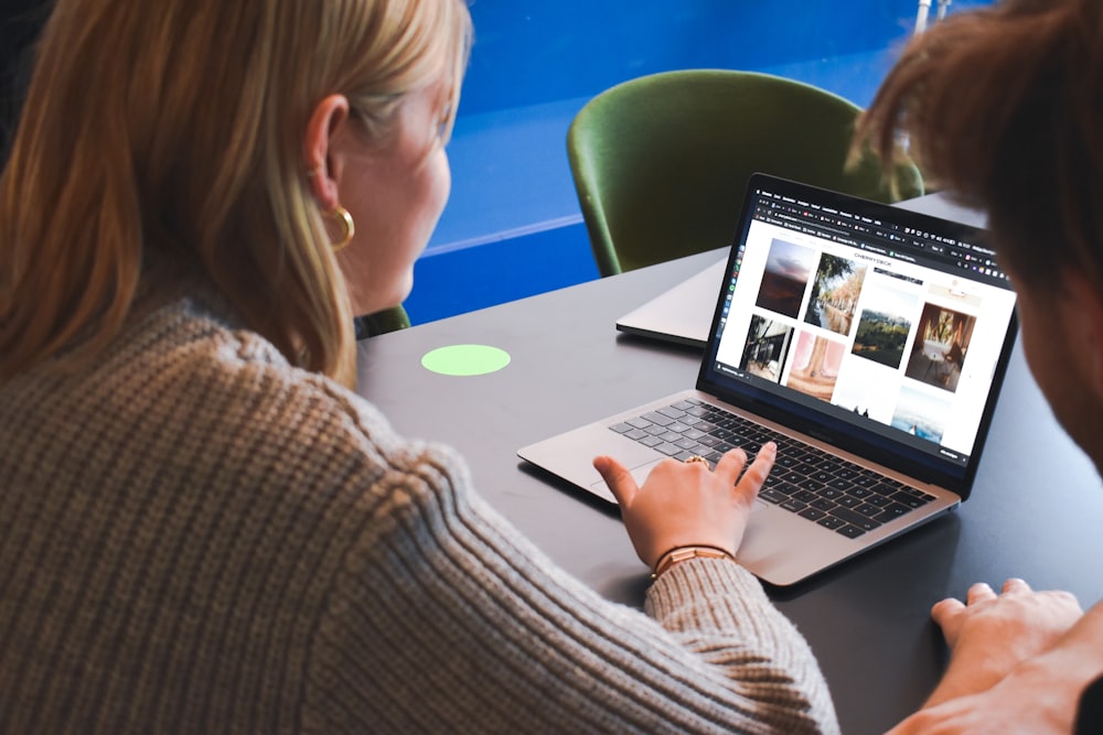 woman in gray sweater using macbook pro