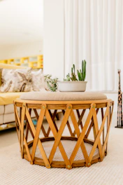 Round coffee table with a natural wood finish, styled with a stack of books and a small plant.