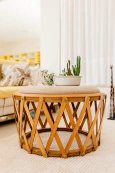 Round coffee table with a natural wood finish, styled with a stack of books and a small plant.