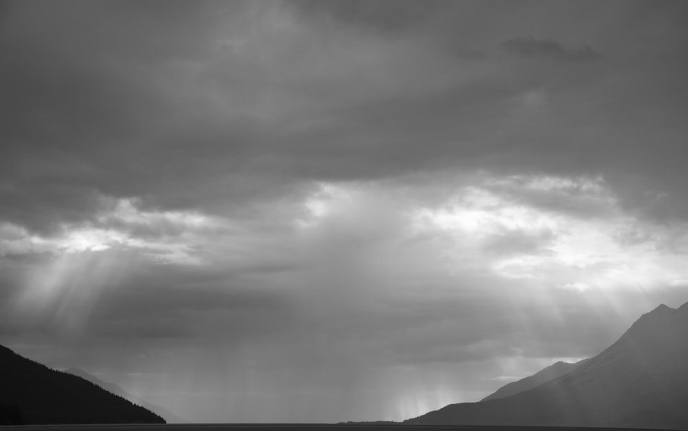 grayscale photo of mountains under cloudy sky