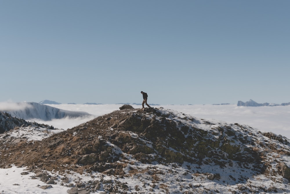 person standing on rock formation covered with snow during daytime