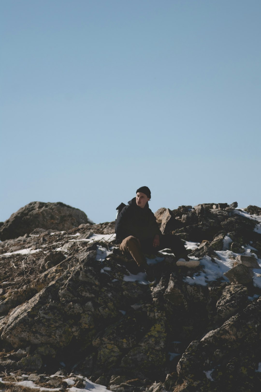 man and woman sitting on rocky mountain during daytime