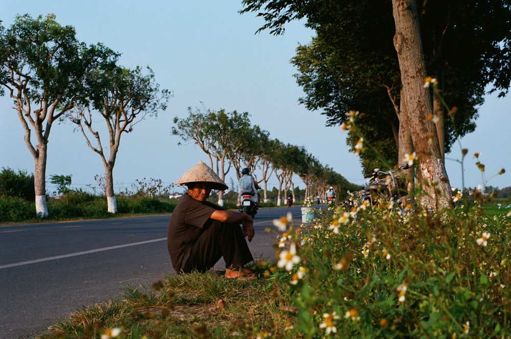 person in black hoodie and brown hat standing on sidewalk during daytime