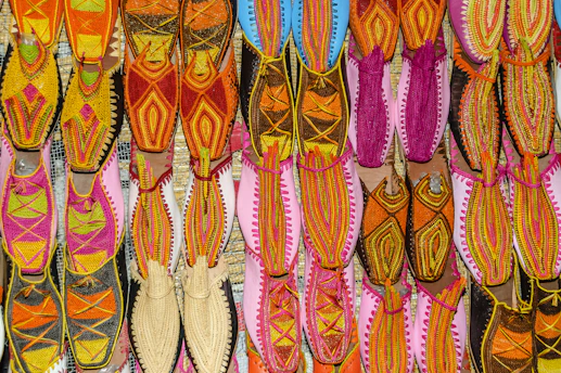 Close-up of handcrafted traditional khussa shoes with intricate embroidery resting on a rustic wooden surface.