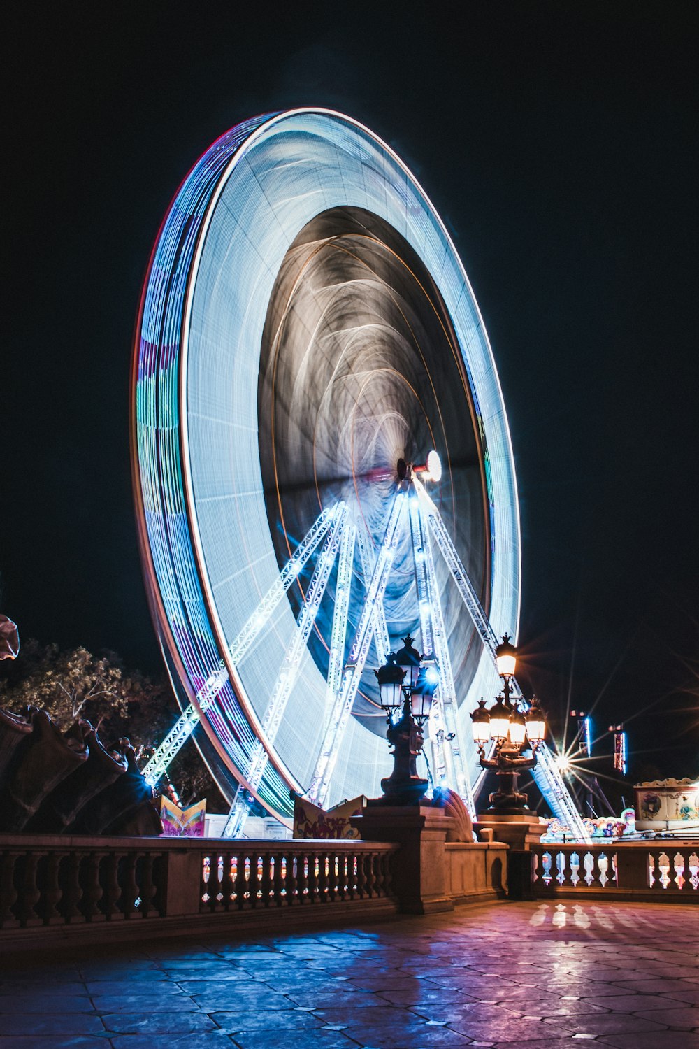 people walking on stairs near white and blue ferris wheel during nighttime