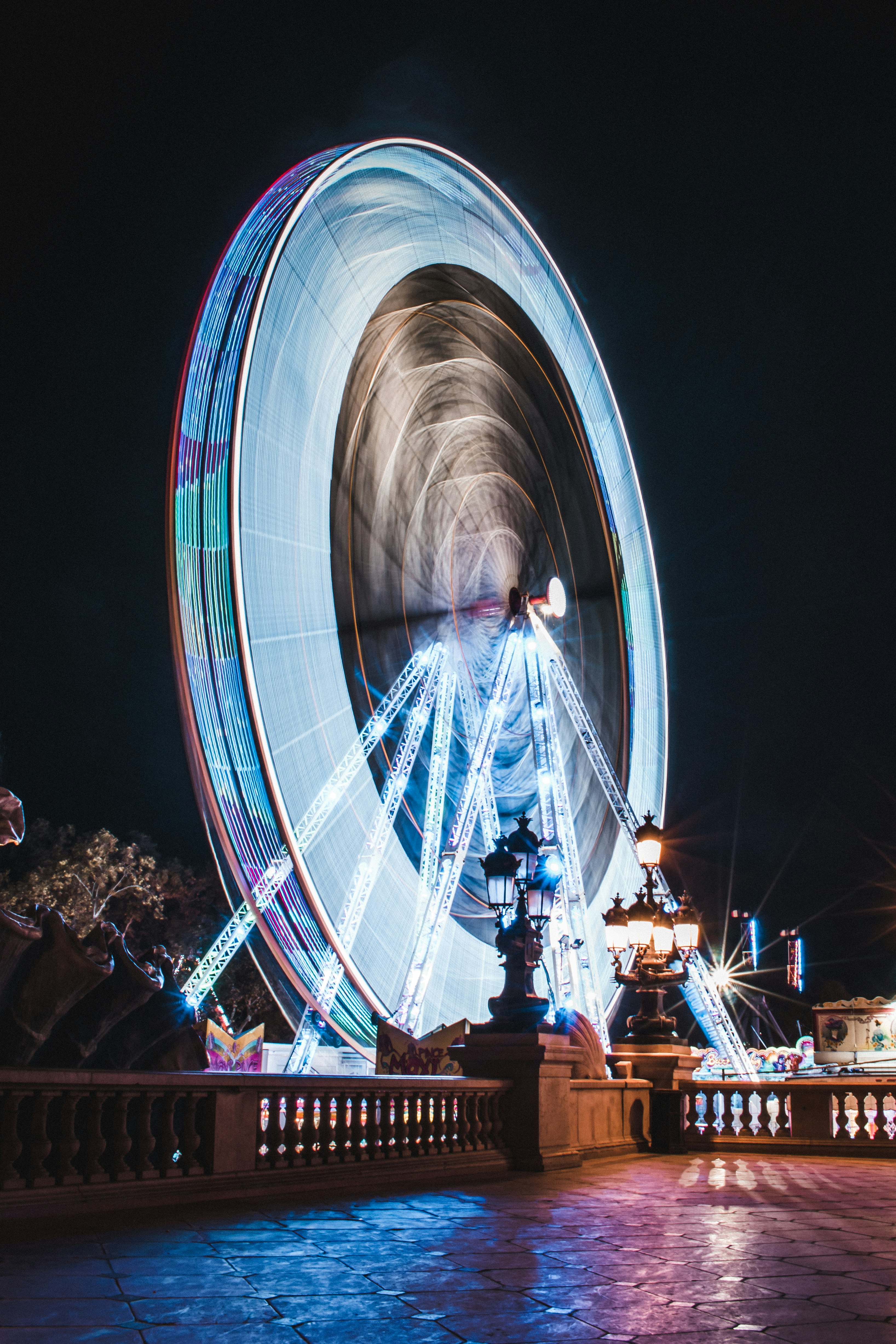 people walking on stairs near white and blue ferris wheel during nighttime