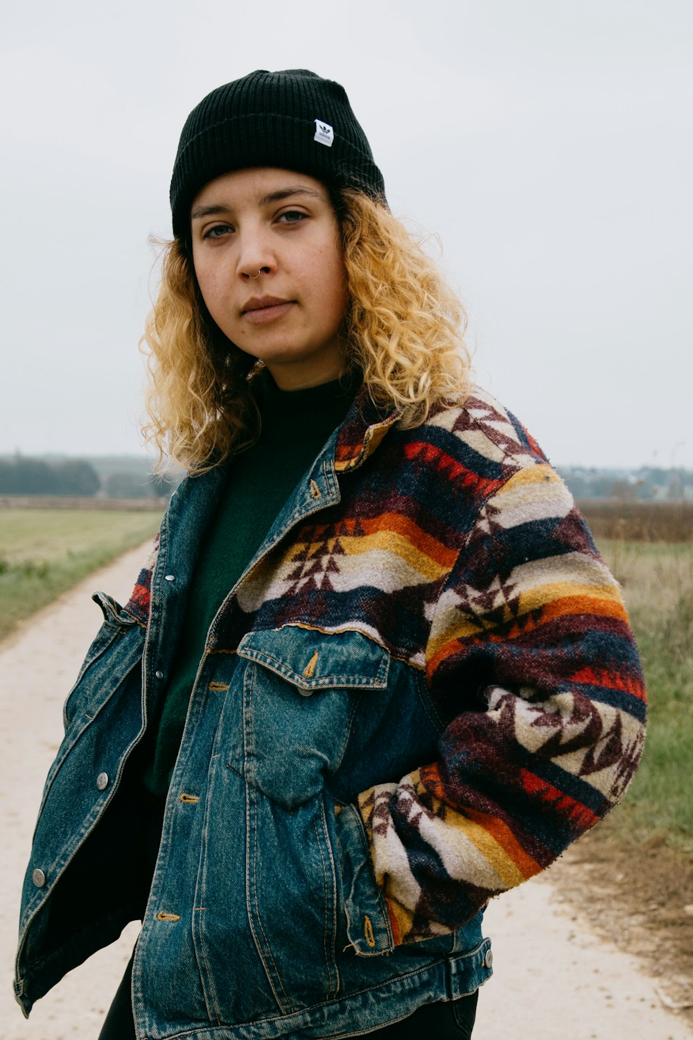 woman in blue denim jacket standing on gray sand during daytime