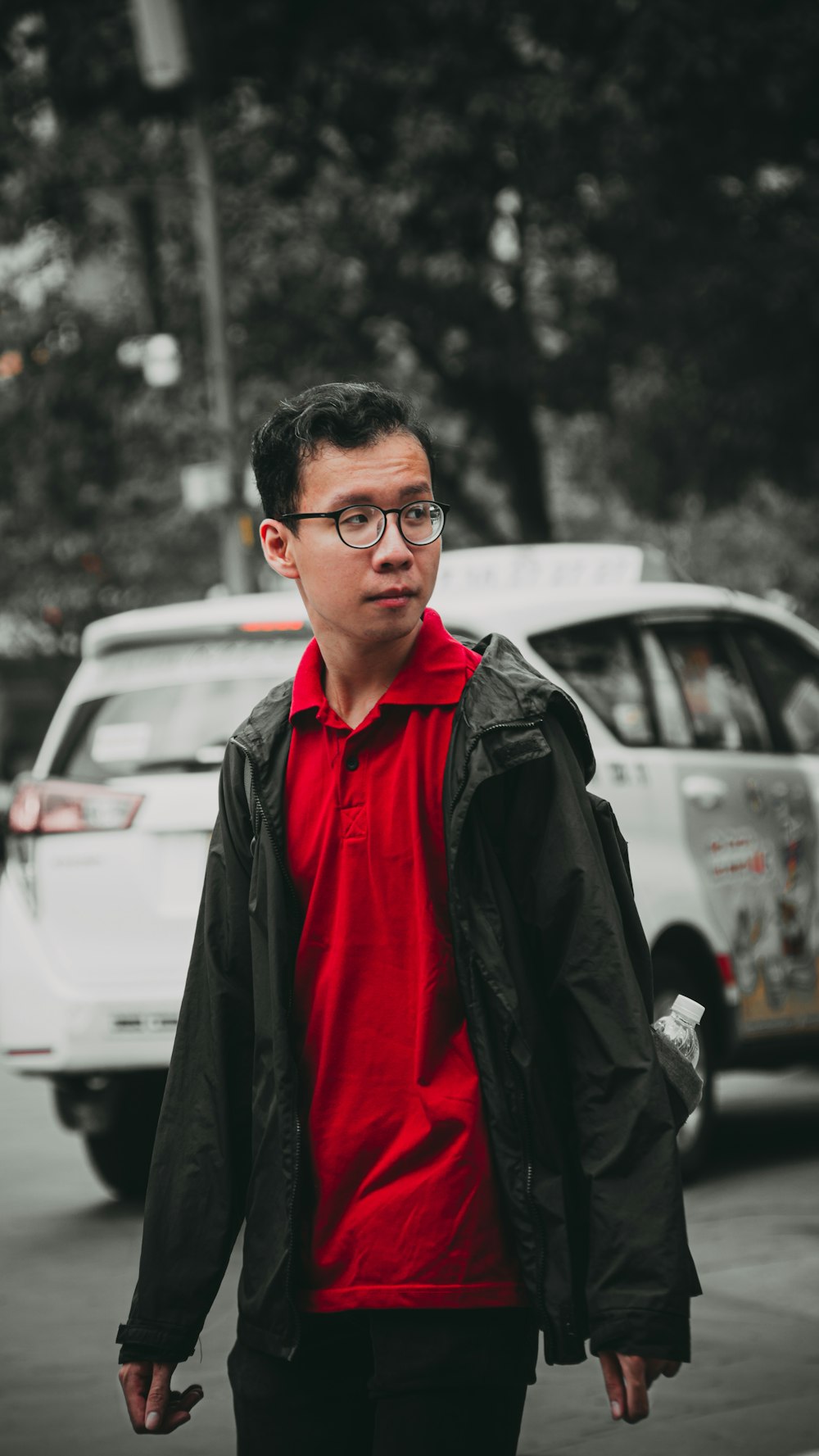 man in black jacket standing near white car