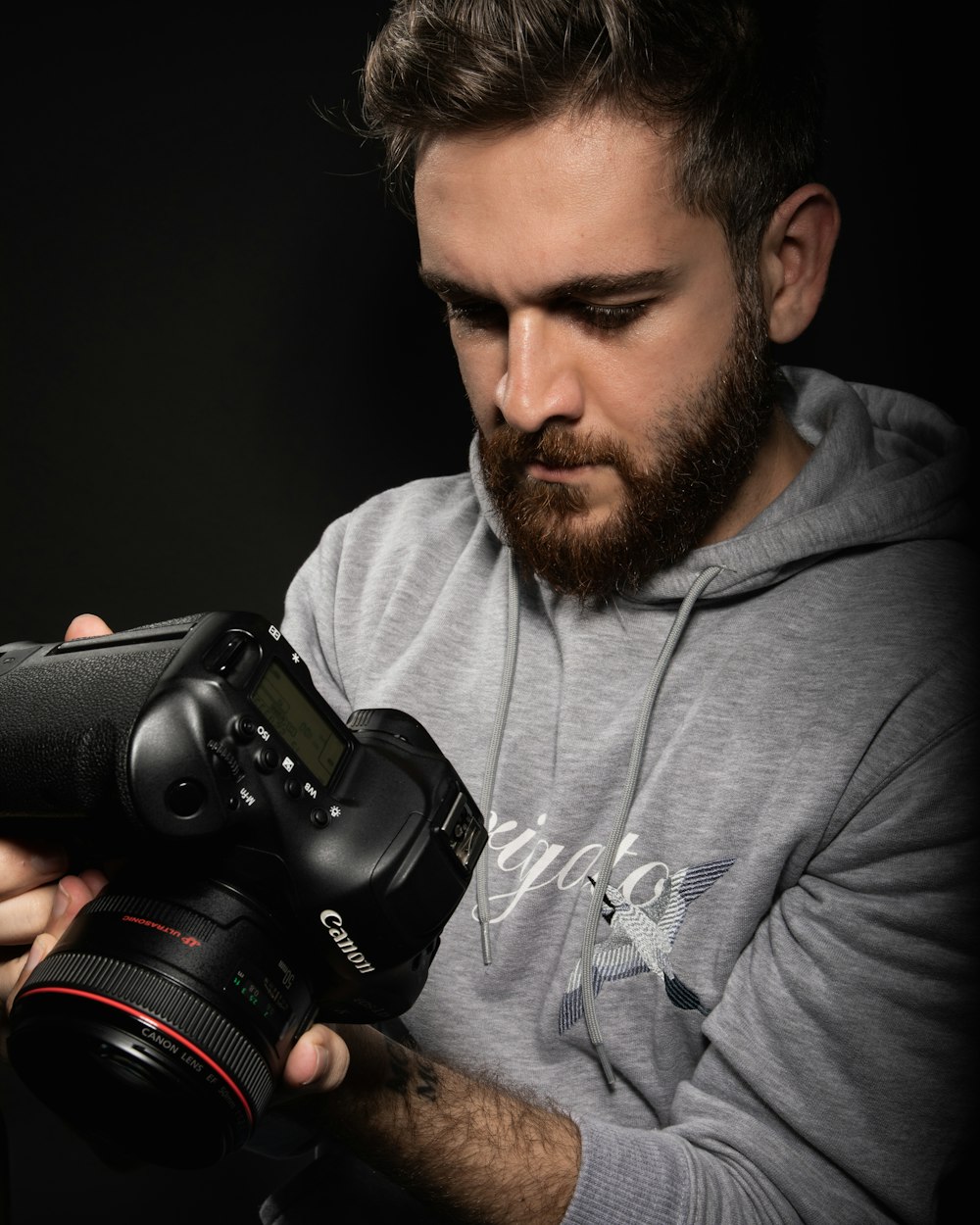 Mann im grauen Rundhalshemd mit schwarzer DSLR-Kamera