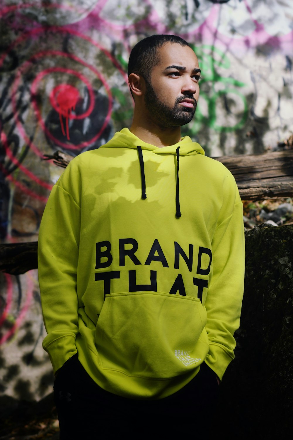 man in yellow and black hoodie standing near red wall